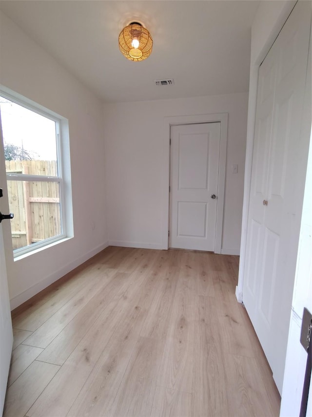 spare room featuring baseboards, visible vents, and light wood finished floors