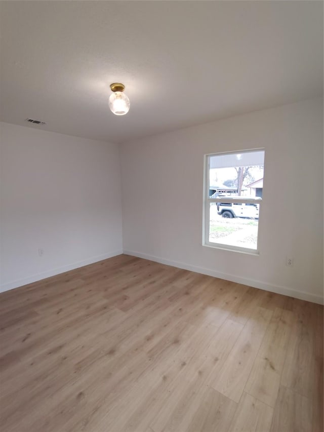 unfurnished room featuring visible vents, light wood-style flooring, and baseboards