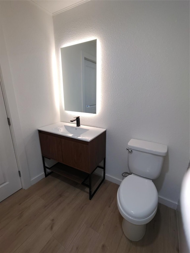 bathroom with vanity, wood finished floors, toilet, and baseboards