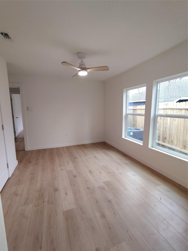 empty room with baseboards, light wood-type flooring, visible vents, and a ceiling fan