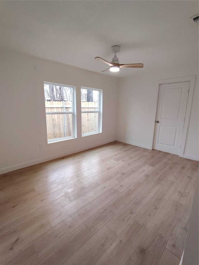 unfurnished room featuring a ceiling fan, baseboards, visible vents, and light wood finished floors