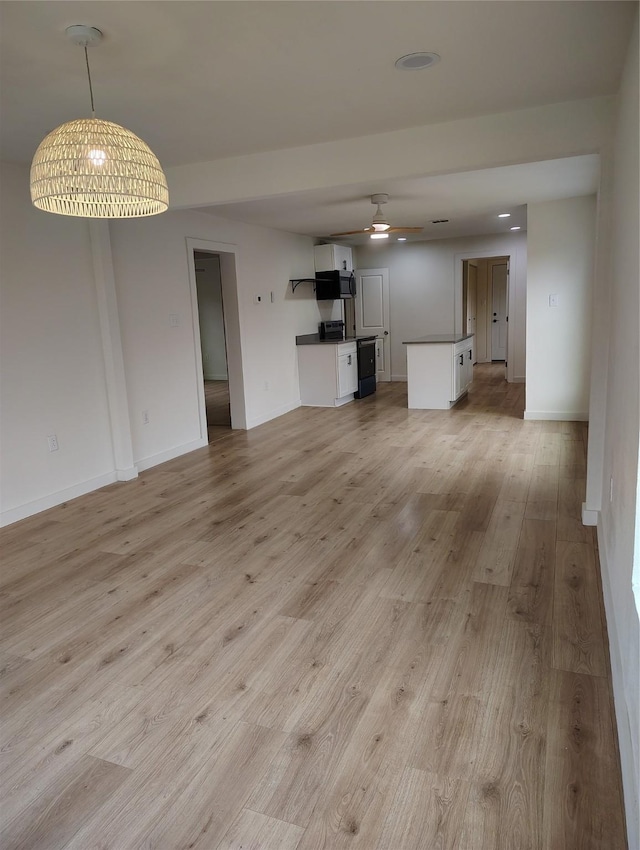 unfurnished living room with light wood finished floors, a ceiling fan, and baseboards