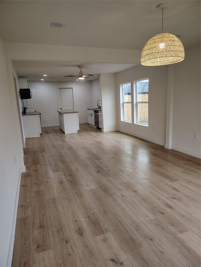 unfurnished living room with baseboards, ceiling fan, and light wood-style floors