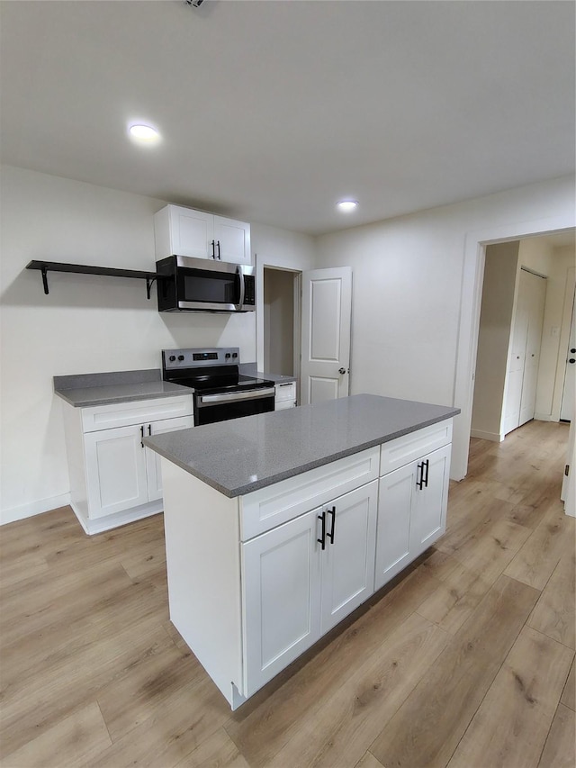 kitchen with stainless steel appliances, white cabinetry, and light wood-style floors