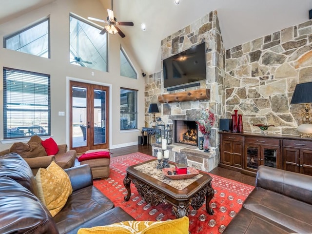 living room with french doors, a stone fireplace, high vaulted ceiling, dark hardwood / wood-style flooring, and ceiling fan