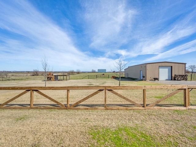 view of yard with a garage, an outdoor structure, and a rural view