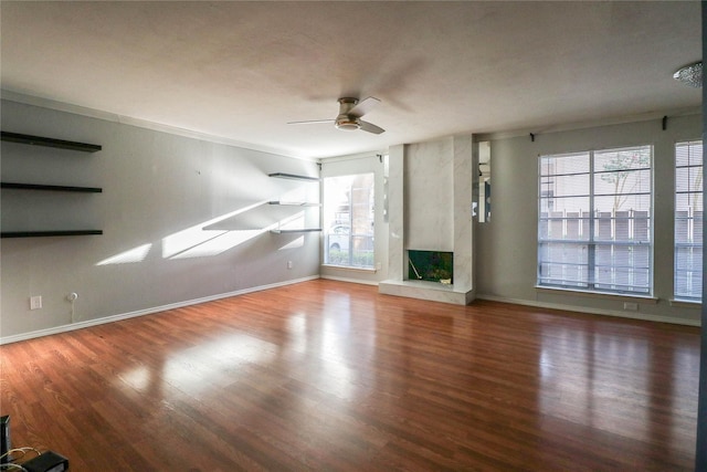 unfurnished living room with wood-type flooring, a large fireplace, and ceiling fan