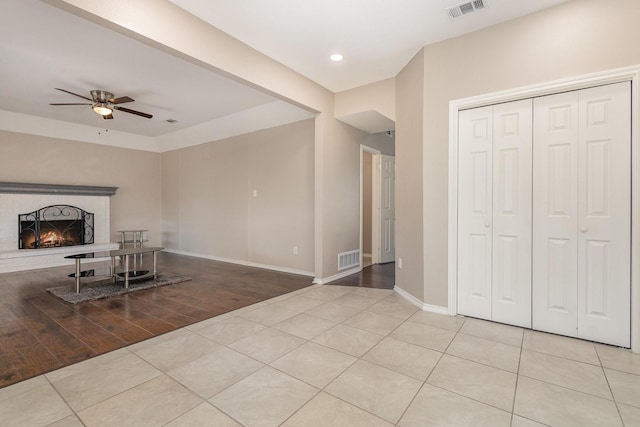 unfurnished living room featuring light tile patterned floors, a brick fireplace, and ceiling fan