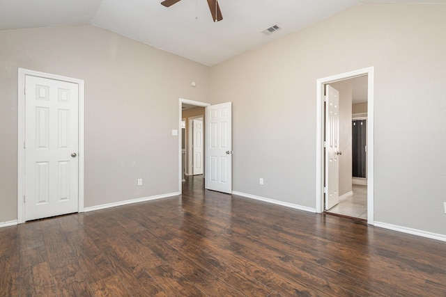 unfurnished bedroom featuring dark wood-type flooring, ensuite bathroom, and vaulted ceiling