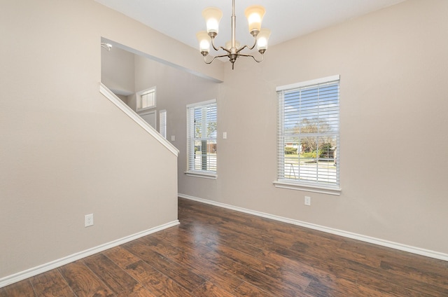 spare room with dark hardwood / wood-style floors and a notable chandelier