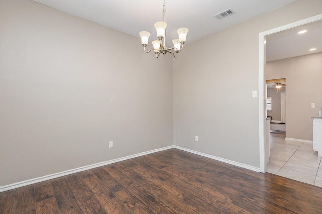 unfurnished room with an inviting chandelier and wood-type flooring