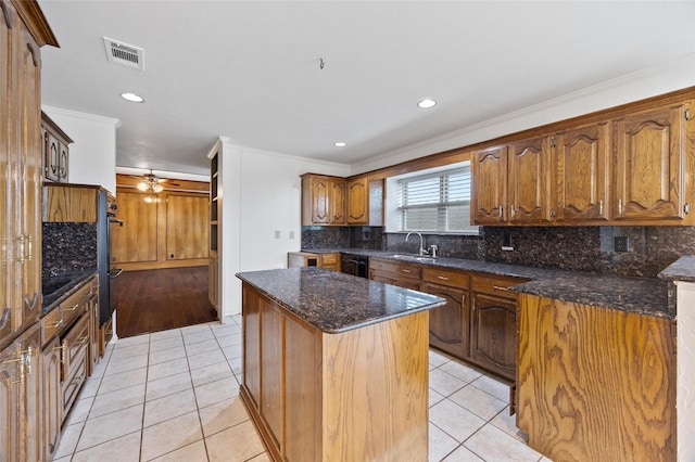 kitchen featuring sink, light tile patterned floors, dark stone counters, and a kitchen island