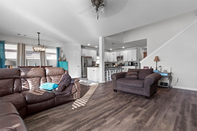 living room with dark hardwood / wood-style floors and ceiling fan with notable chandelier