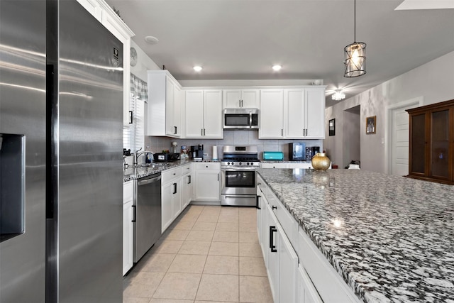 kitchen featuring dark stone countertops, stainless steel appliances, backsplash, and white cabinets