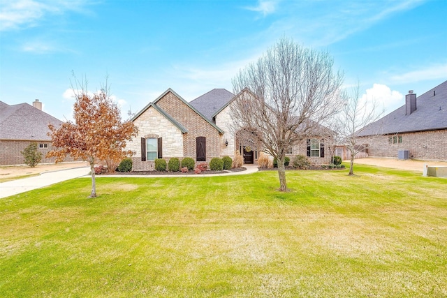 french country home with central AC unit and a front lawn