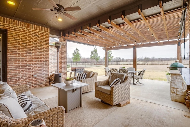 view of patio with ceiling fan, an outdoor living space, a pergola, and a rural view