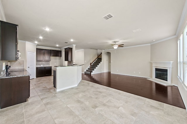 kitchen featuring backsplash, ornamental molding, light stone counters, ceiling fan, and light hardwood / wood-style floors