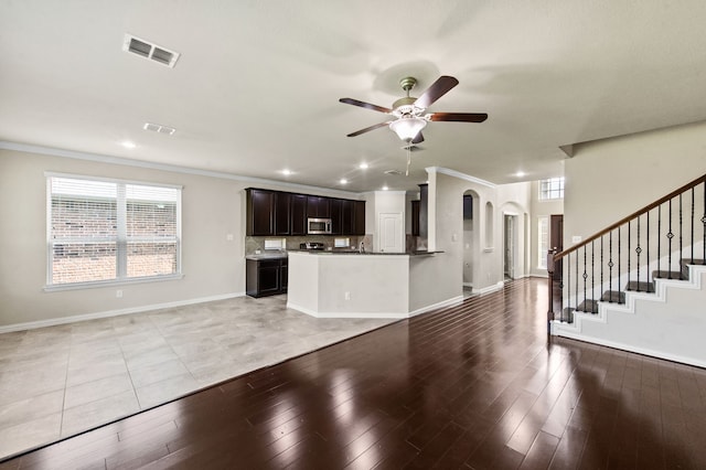 unfurnished living room with ceiling fan, ornamental molding, and light wood-type flooring