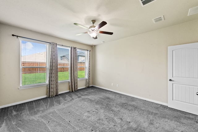 spare room featuring dark carpet and ceiling fan