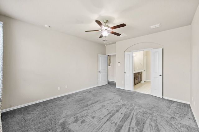 unfurnished bedroom featuring light carpet, ensuite bath, and ceiling fan