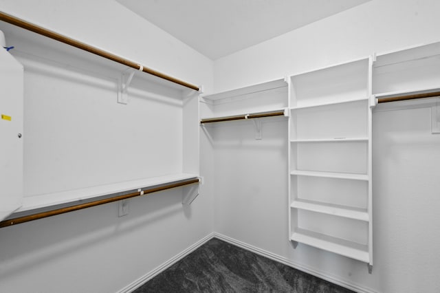 walk in closet featuring dark carpet