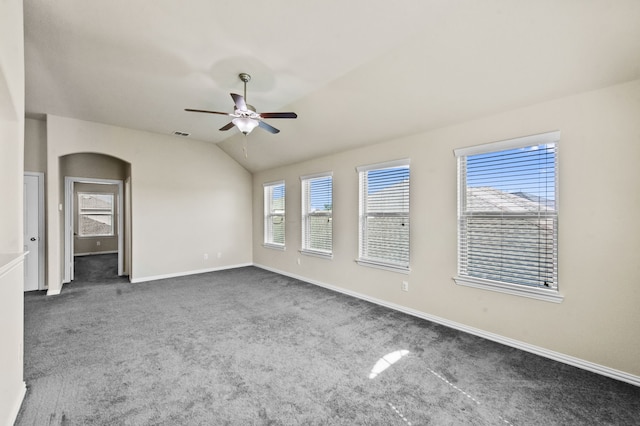 unfurnished room with dark colored carpet, vaulted ceiling, and ceiling fan