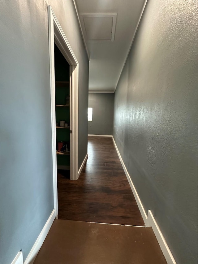 corridor featuring attic access, baseboards, and wood finished floors