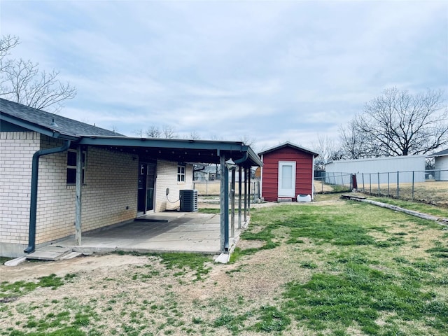 view of yard featuring an outbuilding, a patio, a shed, fence, and central AC unit