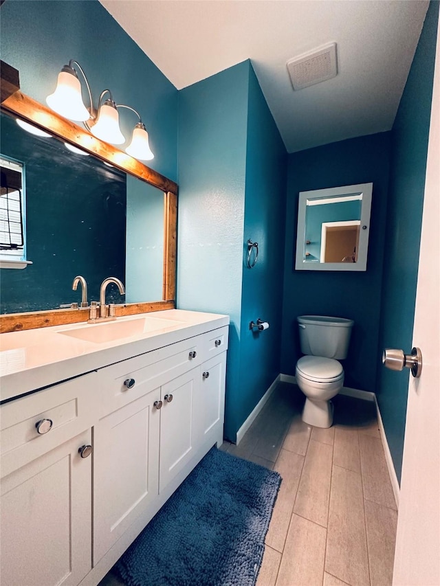 bathroom featuring vanity, toilet, baseboards, and visible vents