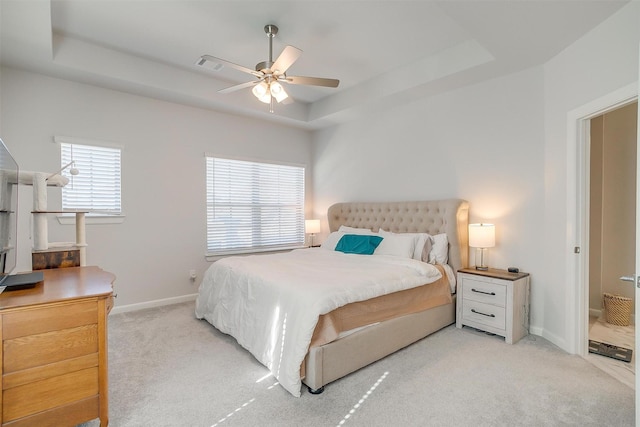 carpeted bedroom with a raised ceiling and ceiling fan