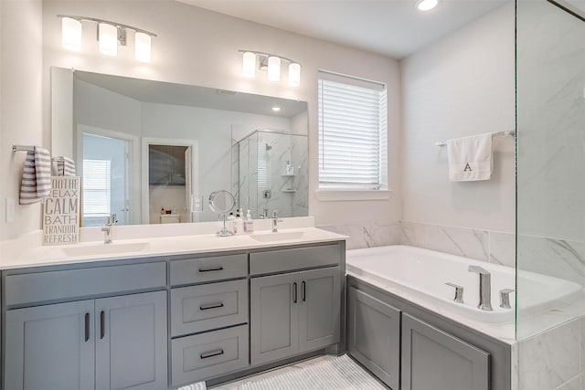 bathroom with a healthy amount of sunlight, independent shower and bath, and vanity