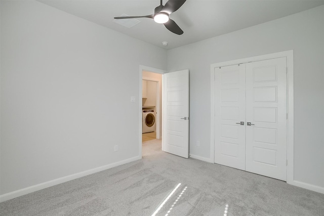 unfurnished bedroom featuring washer / clothes dryer, light colored carpet, ceiling fan, and a closet