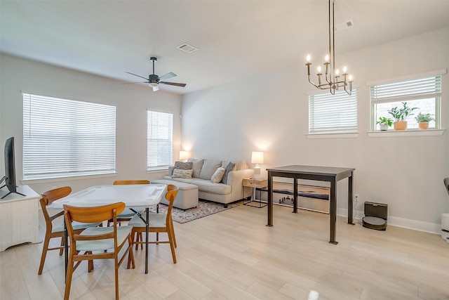 dining room with light hardwood / wood-style flooring, ceiling fan with notable chandelier, and plenty of natural light