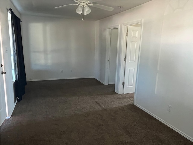 spare room with ceiling fan and dark carpet