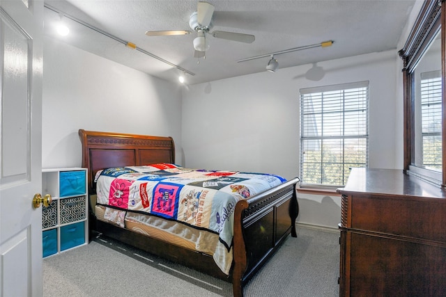 bedroom with ceiling fan, light carpet, and a textured ceiling