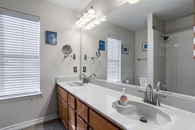 bathroom with vanity, tile patterned floors, toilet, and a tile shower