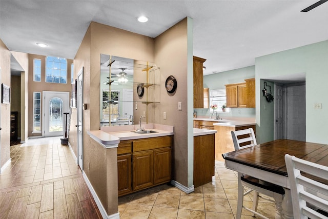 kitchen featuring light tile patterned flooring, ceiling fan, kitchen peninsula, and sink