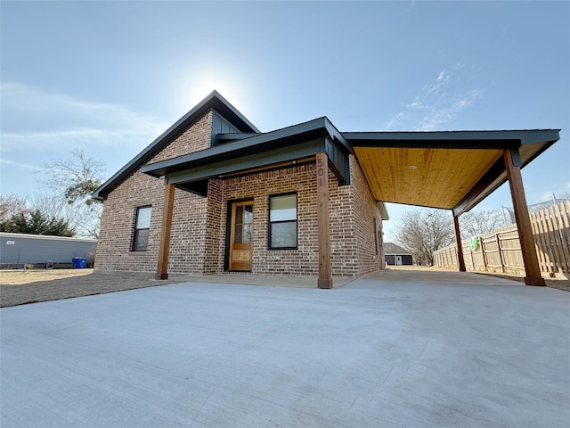 exterior space with driveway, fence, a carport, and brick siding