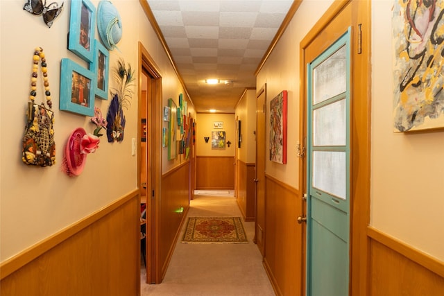 hall featuring crown molding, light colored carpet, and wooden walls