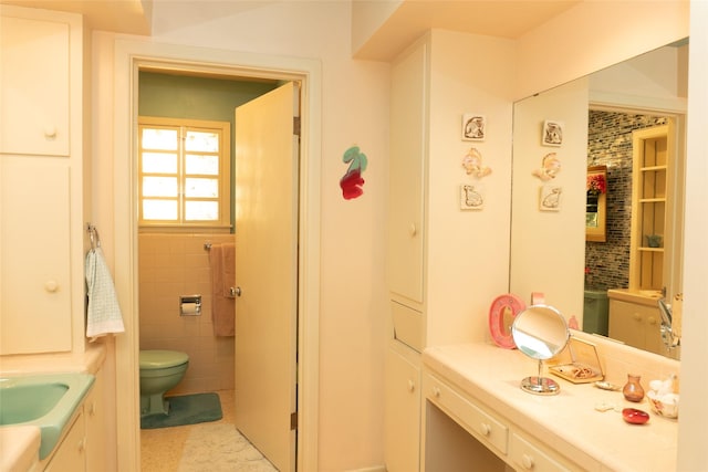 bathroom with vanity, toilet, and tile walls