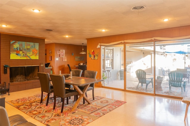 dining room with a brick fireplace and wooden walls