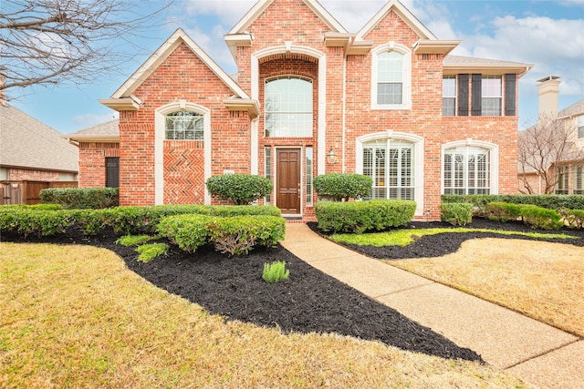 traditional home featuring a front lawn and brick siding