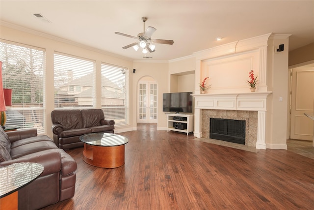 living room featuring dark wood-type flooring, a tile fireplace, ceiling fan, ornamental molding, and french doors