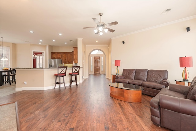 living room with a ceiling fan, wood finished floors, crown molding, recessed lighting, and arched walkways