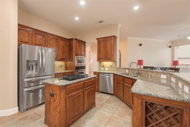 kitchen with stainless steel appliances, tasteful backsplash, a sink, light stone countertops, and a peninsula