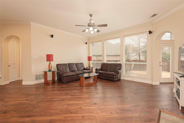living room featuring arched walkways, ceiling fan, dark wood-type flooring, crown molding, and baseboards