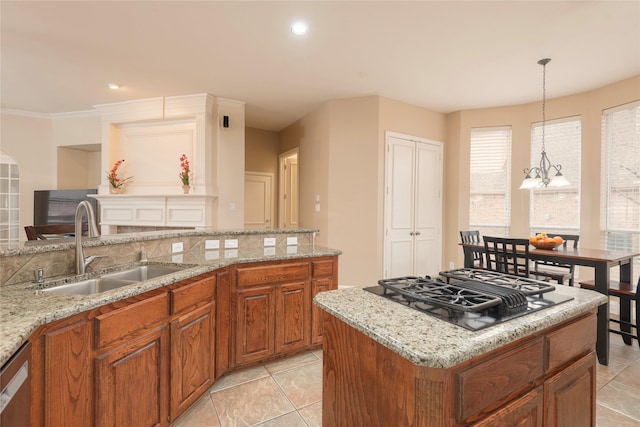 kitchen with black gas stovetop, a sink, brown cabinetry, a kitchen island, and light stone counters