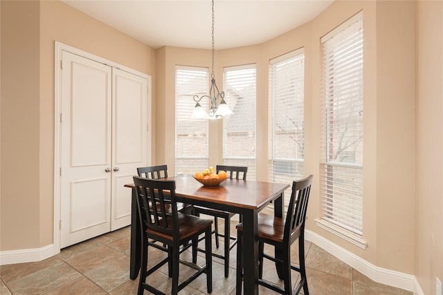 dining space featuring baseboards and a chandelier
