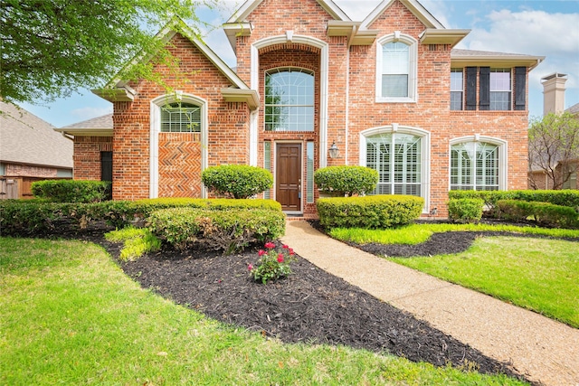 traditional home with brick siding and a front lawn