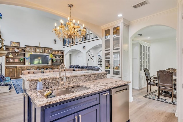 kitchen featuring sink, light stone counters, blue cabinetry, and light hardwood / wood-style flooring